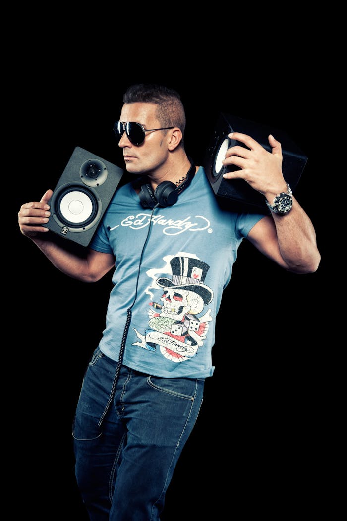 team-05 Portrait of a stylish male DJ holding speakers in a studio.